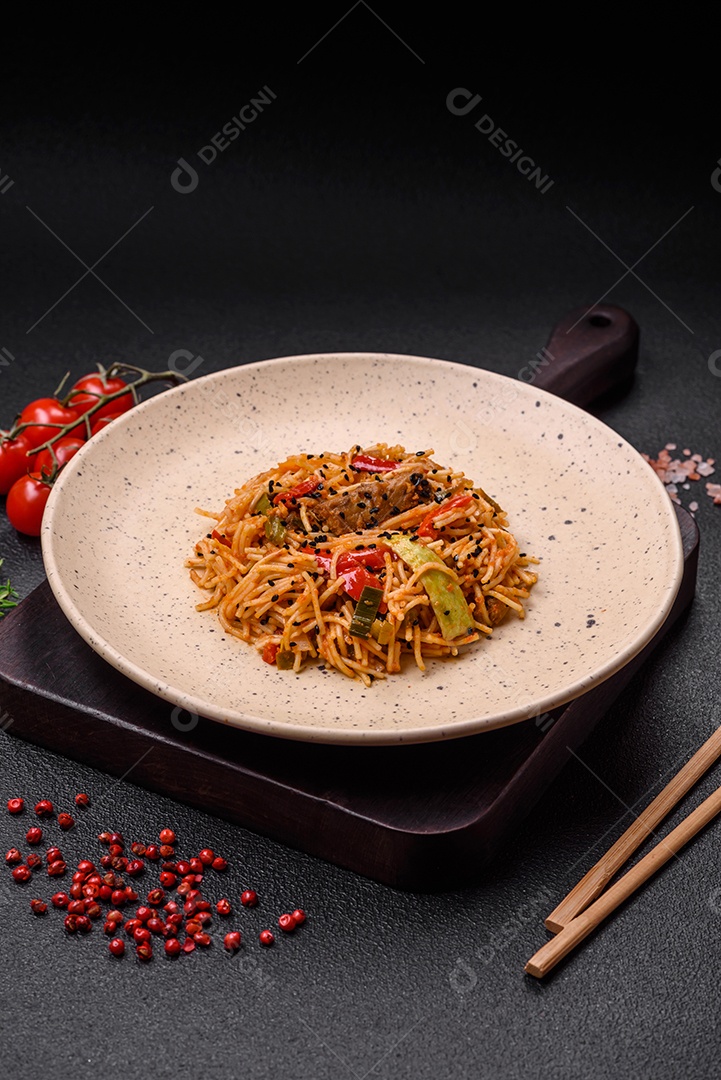 Delicioso macarrão udon com carne ou frutos do mar, legumes, sal e especiarias sobre um fundo escuro de concreto
