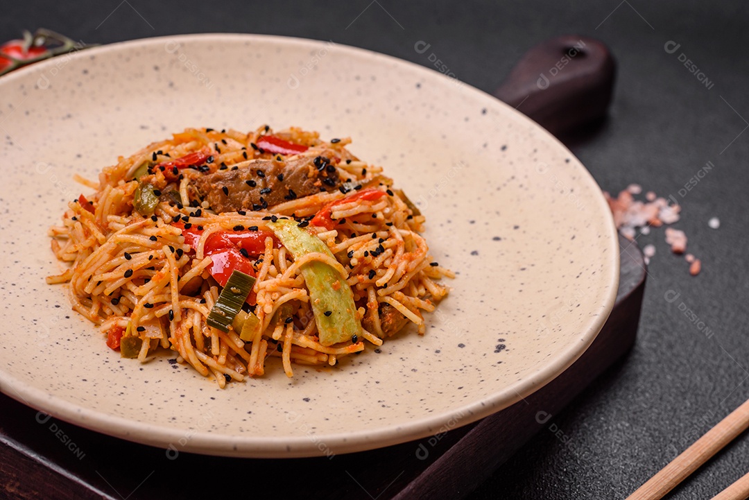 Delicioso macarrão udon com carne ou frutos do mar, legumes, sal e especiarias sobre um fundo escuro de concreto