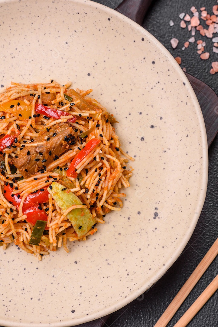 Delicioso macarrão udon com carne ou frutos do mar, legumes, sal e especiarias sobre um fundo escuro de concreto
