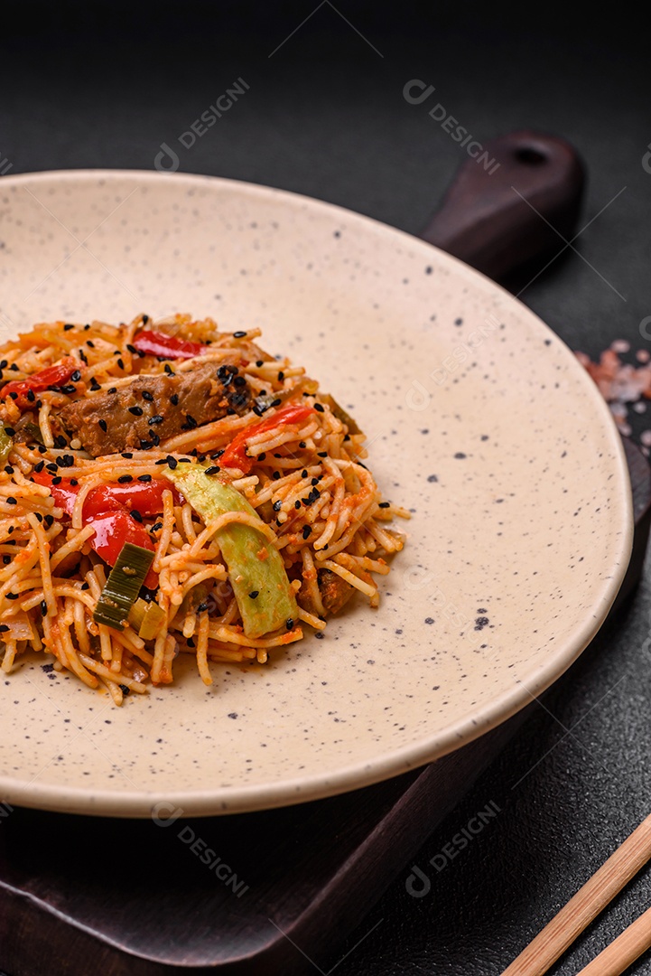 Delicioso macarrão udon com carne ou frutos do mar, legumes, sal e especiarias sobre um fundo escuro de concreto