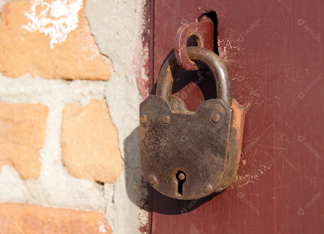 Cadeado velho em portas vermelhas ao lado parede de tijolos