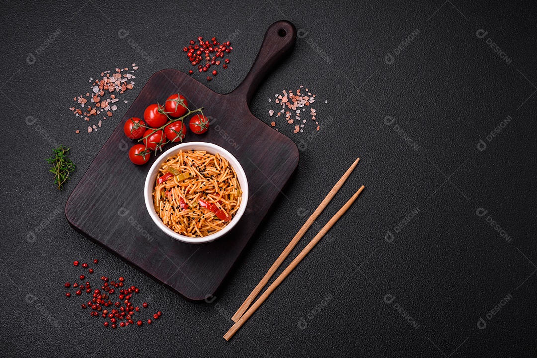 Delicioso macarrão udon com carne ou frutos do mar, legumes, sal e especiarias sobre um fundo escuro de concreto