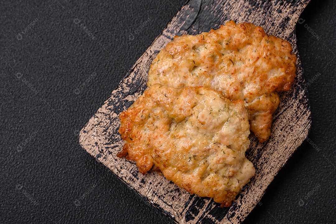 Deliciosas costeletas de frango ou peru assadas com sal, especiarias e ervas sobre um fundo escuro de concreto