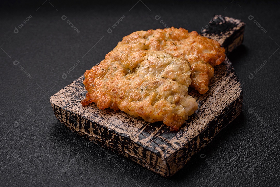 Deliciosas costeletas de frango ou peru assadas com sal, especiarias e ervas sobre um fundo escuro de concreto