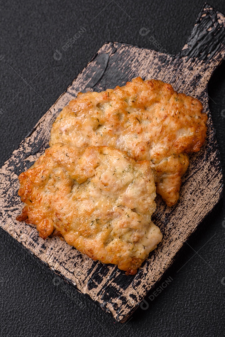 Deliciosas costeletas de frango ou peru assadas com sal, especiarias e ervas sobre um fundo escuro de concreto
