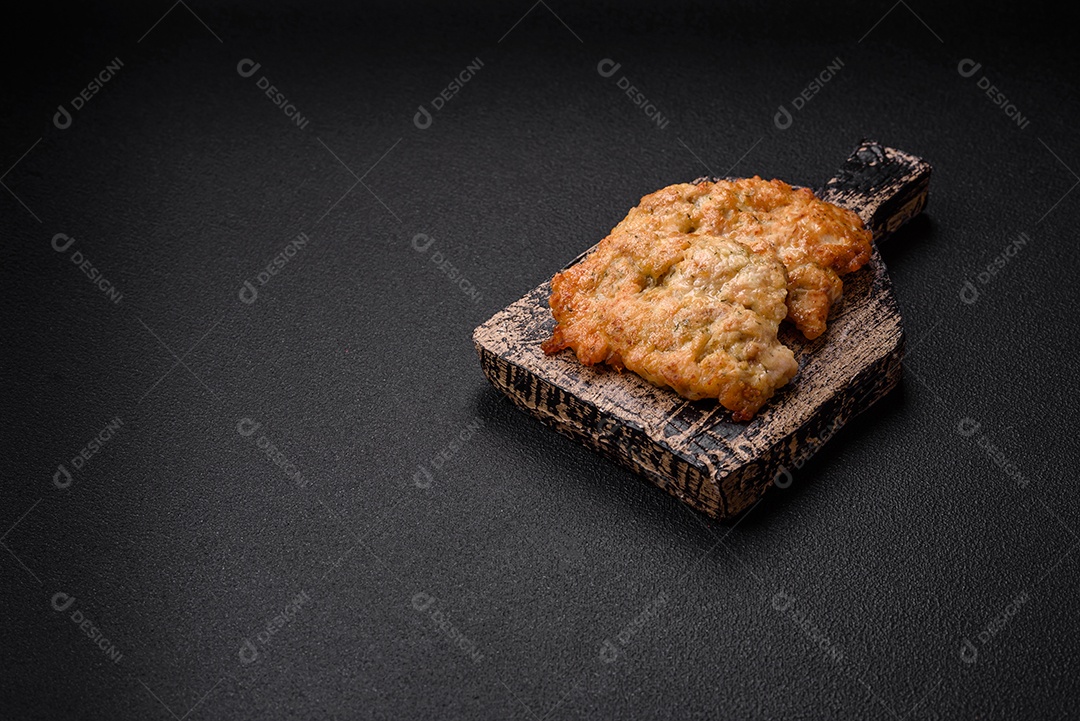 Deliciosas costeletas de frango ou peru assadas com sal, especiarias e ervas sobre um fundo escuro de concreto