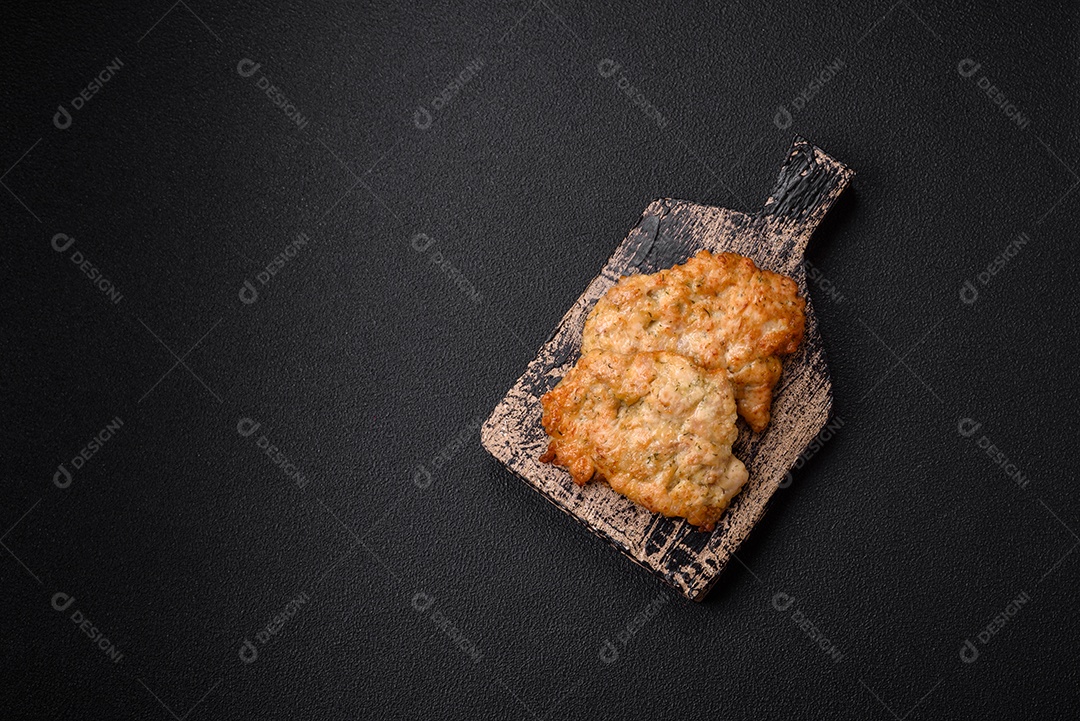 Deliciosas costeletas de frango ou peru assadas com sal, especiarias e ervas sobre um fundo escuro de concreto