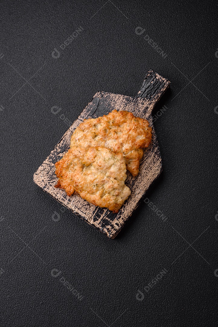 Deliciosas costeletas de frango ou peru assadas com sal, especiarias e ervas sobre um fundo escuro de concreto