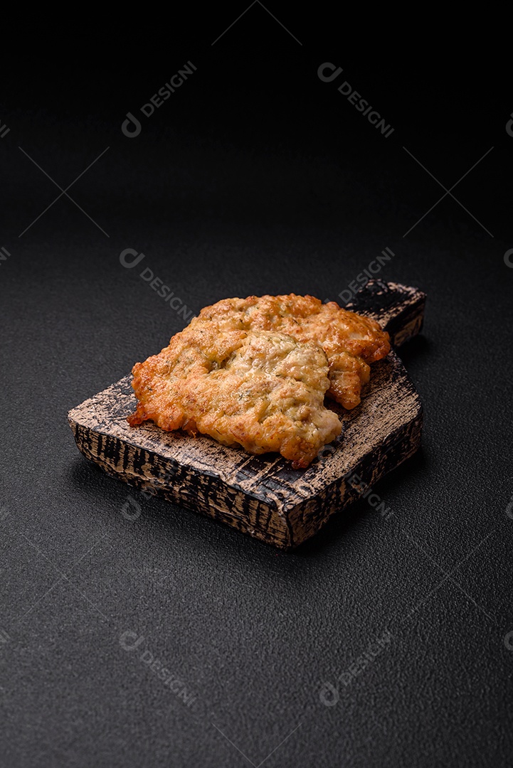 Deliciosas costeletas de frango ou peru assadas com sal, especiarias e ervas sobre um fundo escuro de concreto