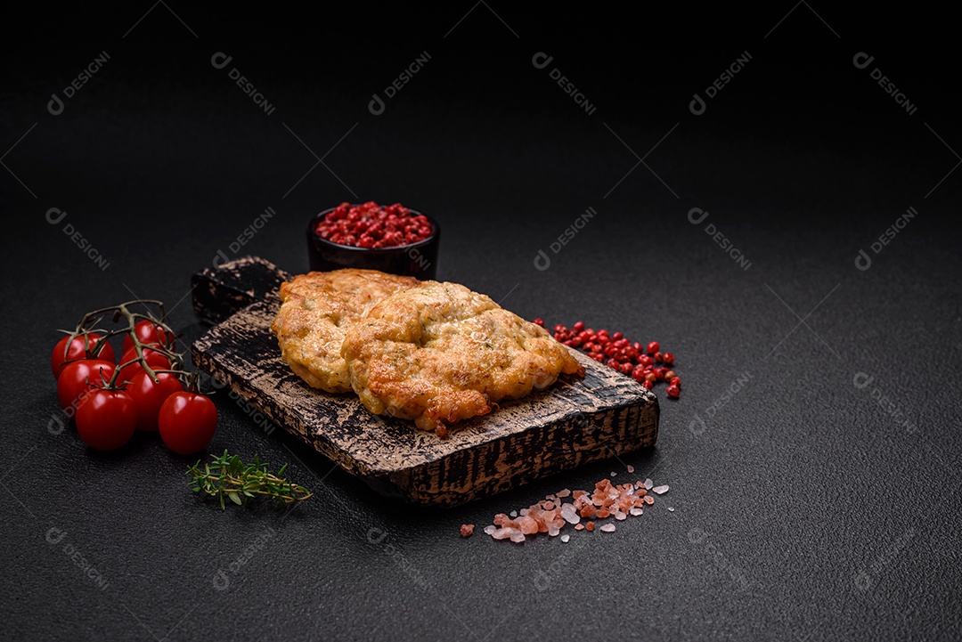 Deliciosas costeletas de frango ou peru assadas com sal, especiarias e ervas sobre um fundo escuro de concreto