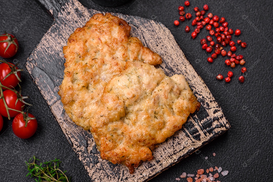 Deliciosas costeletas de frango ou peru assadas com sal, especiarias e ervas sobre um fundo escuro de concreto