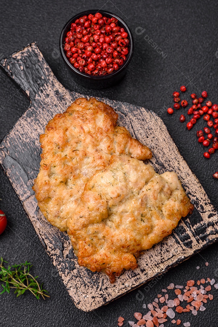 Deliciosas costeletas de frango ou peru assadas com sal, especiarias e ervas sobre um fundo escuro de concreto