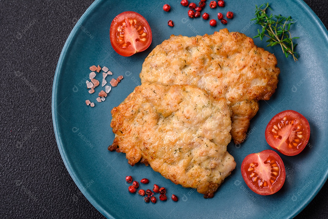 Deliciosas costeletas de frango ou peru assadas com sal, especiarias e ervas sobre um fundo escuro de concreto