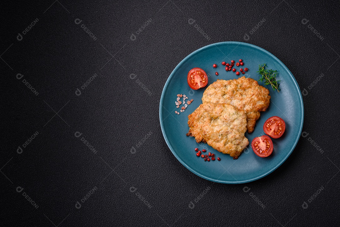 Deliciosas costeletas de frango ou peru assadas com sal, especiarias e ervas sobre um fundo escuro de concreto