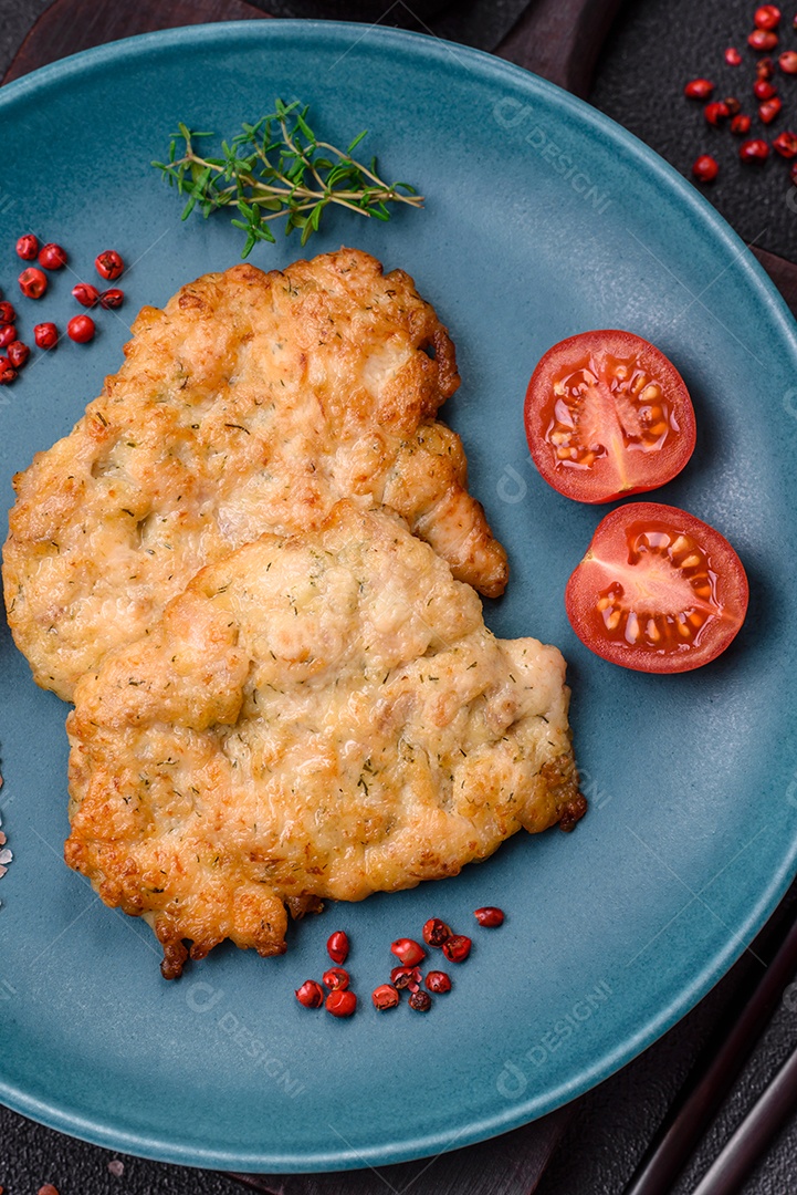 Deliciosas costeletas de frango ou peru assadas com sal, especiarias e ervas sobre um fundo escuro de concreto