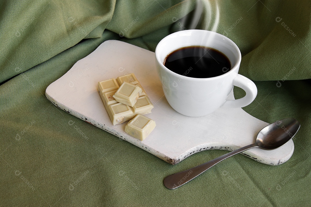 Xícara de café com chocolate e colher em cima da tábua