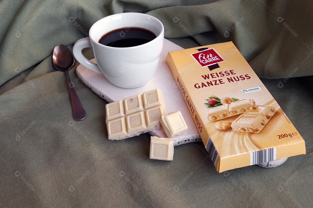 Xícara de café com barras de chocolate em cima de tábua sobre fundo com pano verde