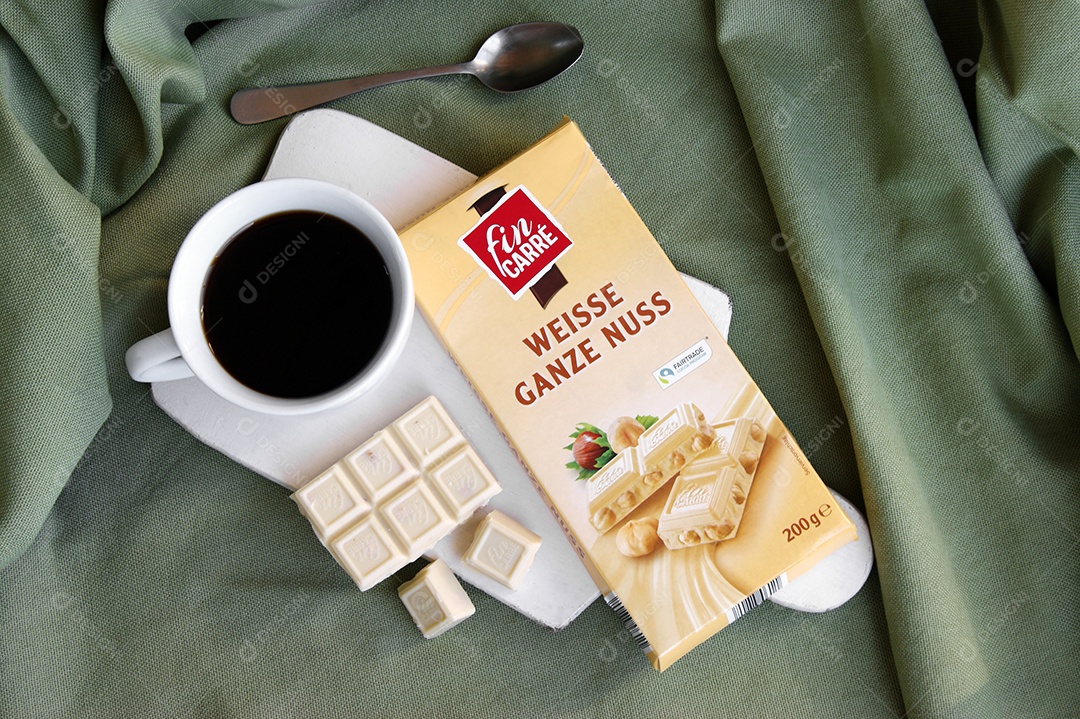 Xícara de café e barra de chocolate sobre uma tábua e colher ao lado