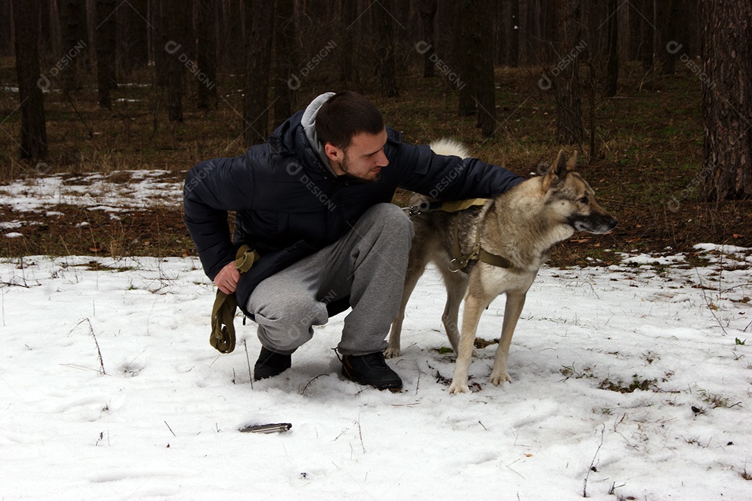 Homem passeando com husky em floresta de neve