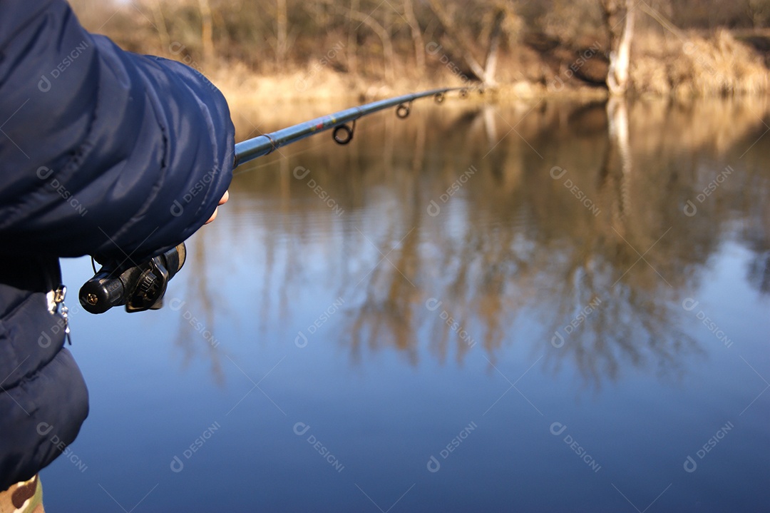 Vara de pesca nas mãos de um pescador no lago