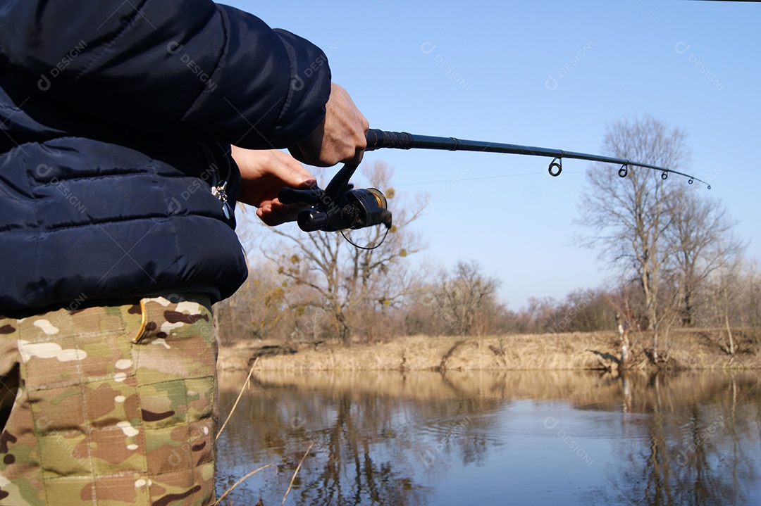 Vara de pesca nas mãos de um pescador no lago