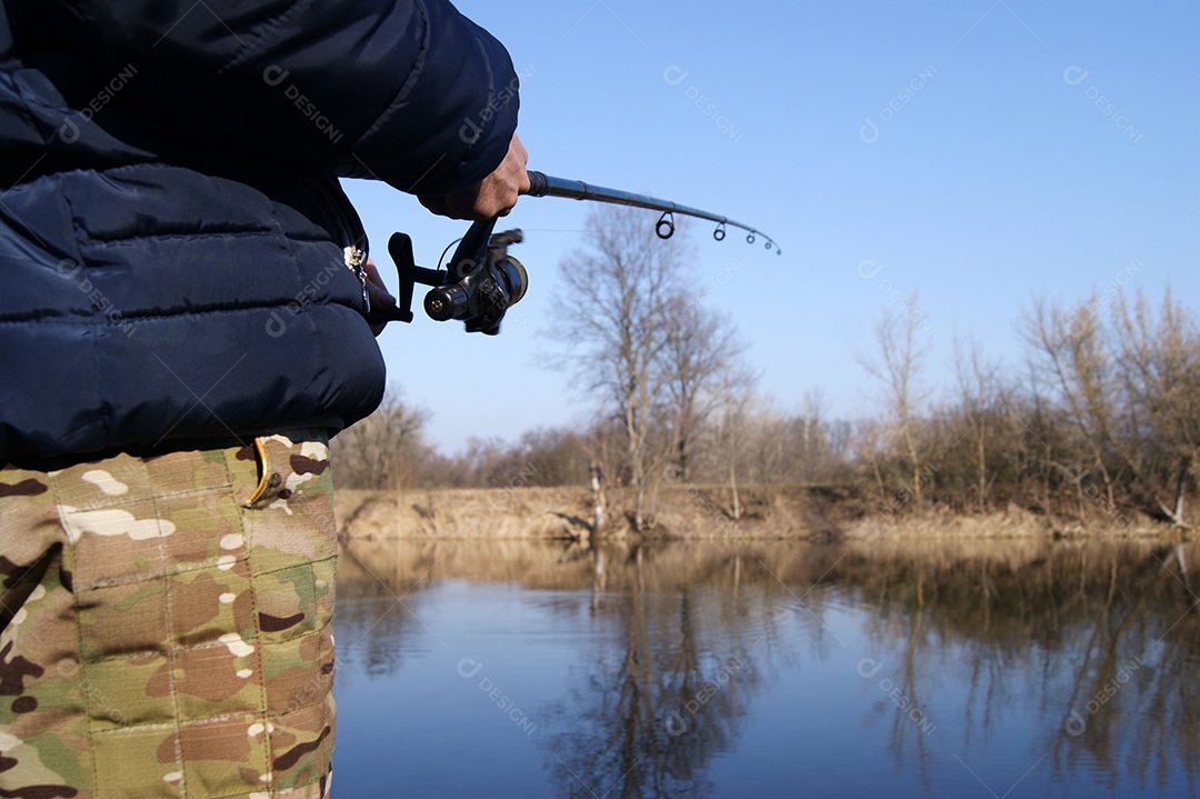 Vara de pesca nas mãos de um pescador no lago