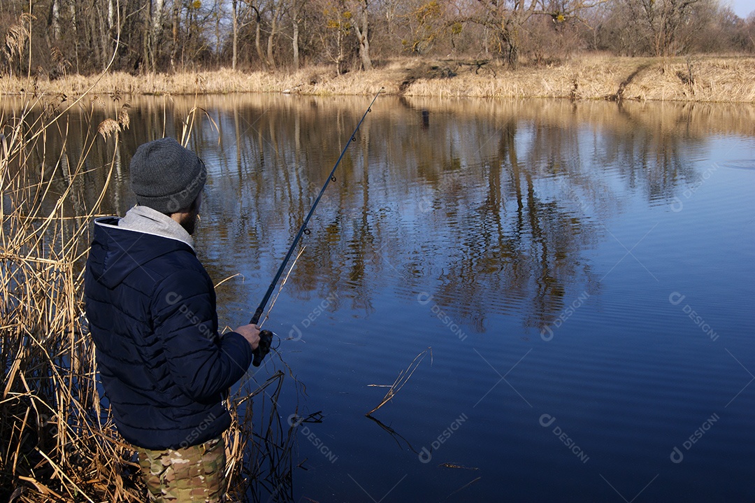 Vara de pesca nas mãos de um pescador no lago