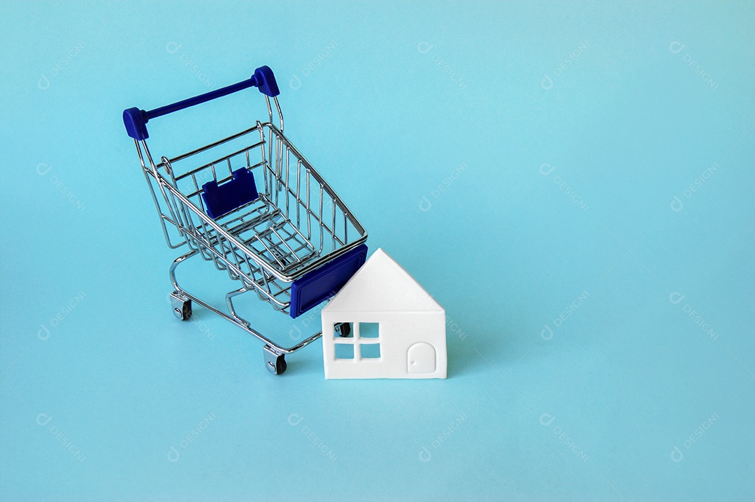 Carrinho de compra com casa de papel ao lado sobre fundo azul