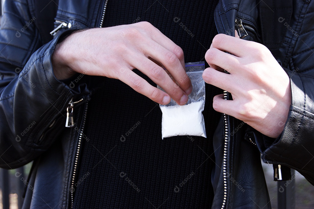 Mãos de homem segurando pacote de cocaína próximo ao peito