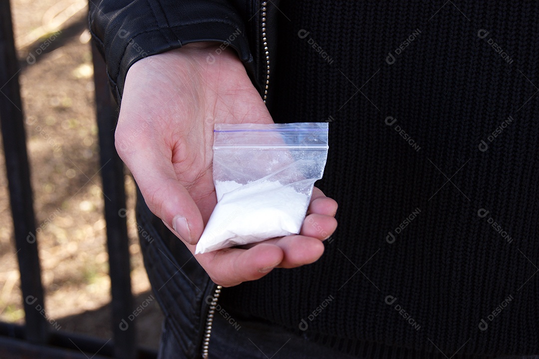 Mão de homem segurando pacote de cocaína