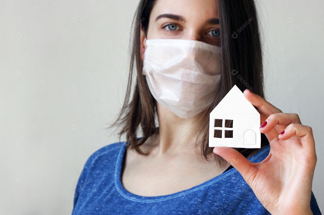 Mulher de máscara segurando uma mini casa de papel