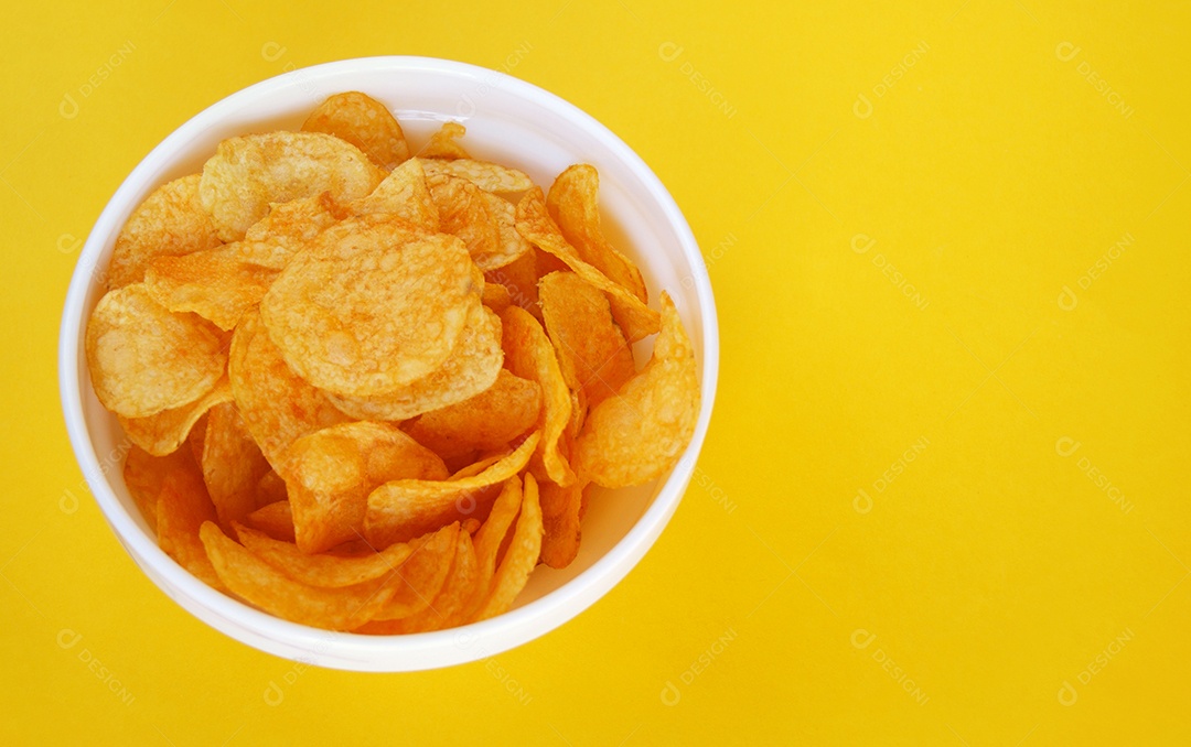 Batata frita chips em vasilha branca sobre fundo amarelo