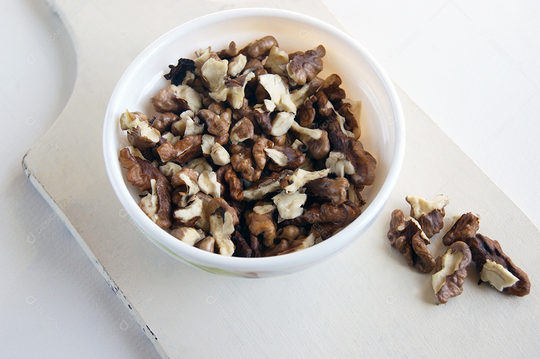 Nozes descascadas em uma vasilha branca sobre uma tábua