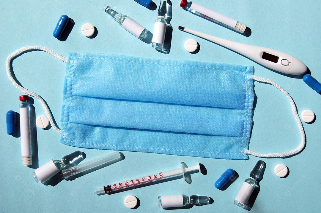 Máscara rodeada de medicamentos e termômetro seringa