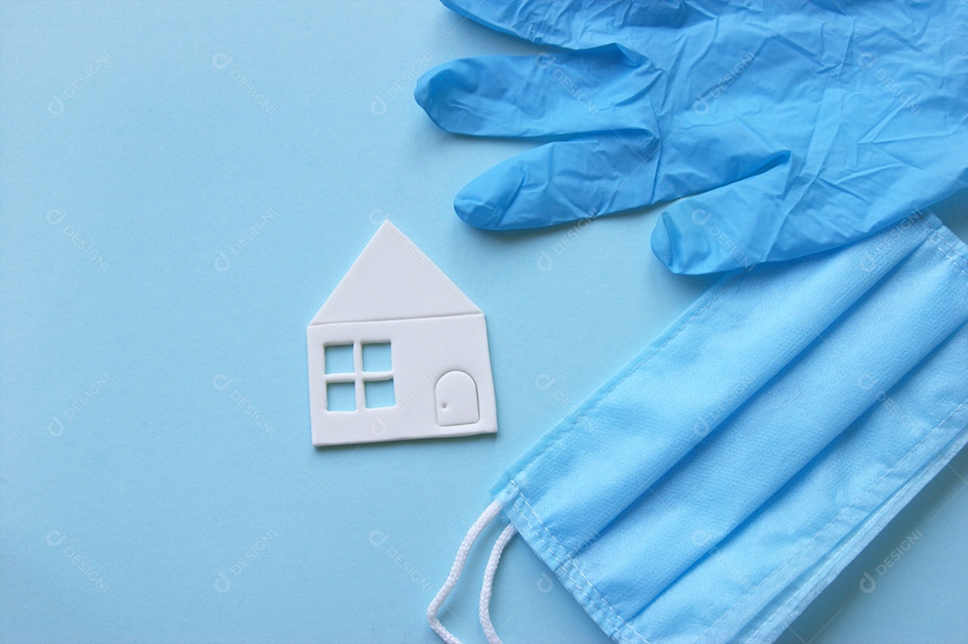 Máscara e luvas junto a uma mini casa branca sobre fundo isolado azul