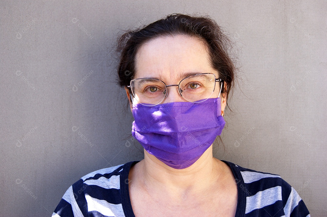 Mulher de olhos claros e de óculos usando máscara roxa