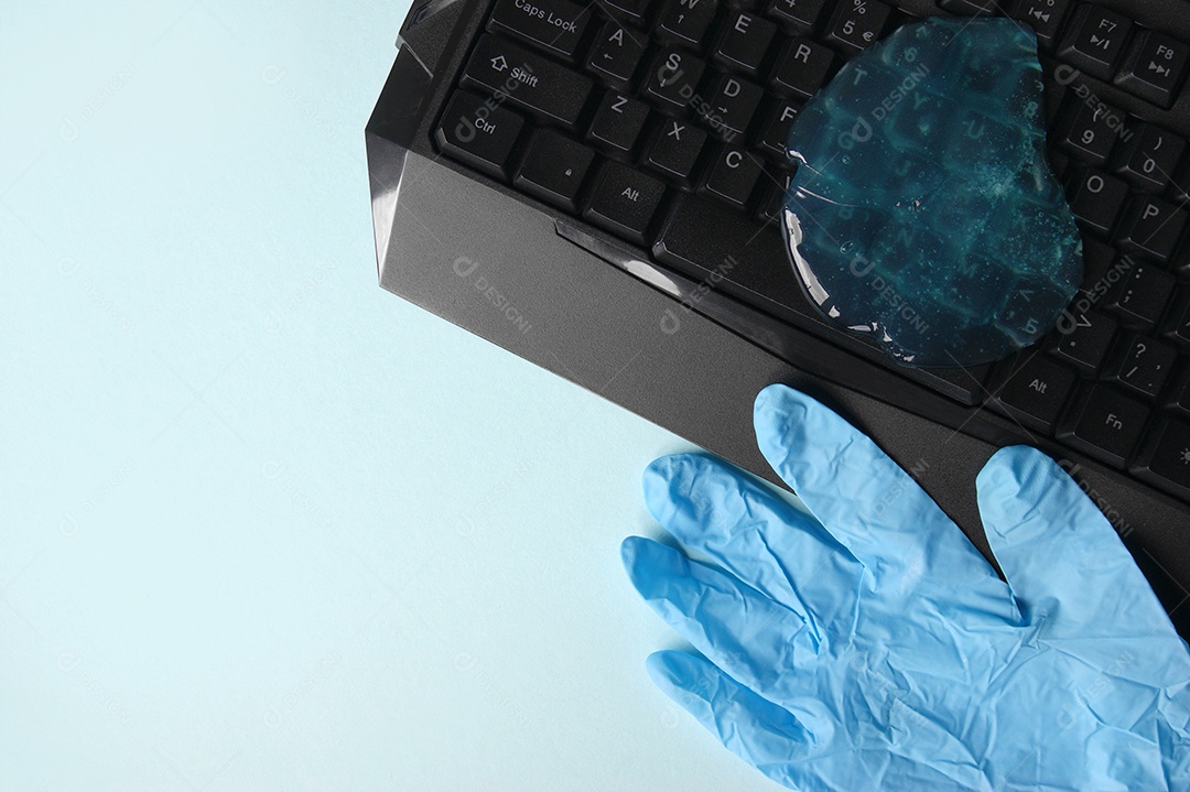 Teclado com gel de limpeza em cima e luva ao lado