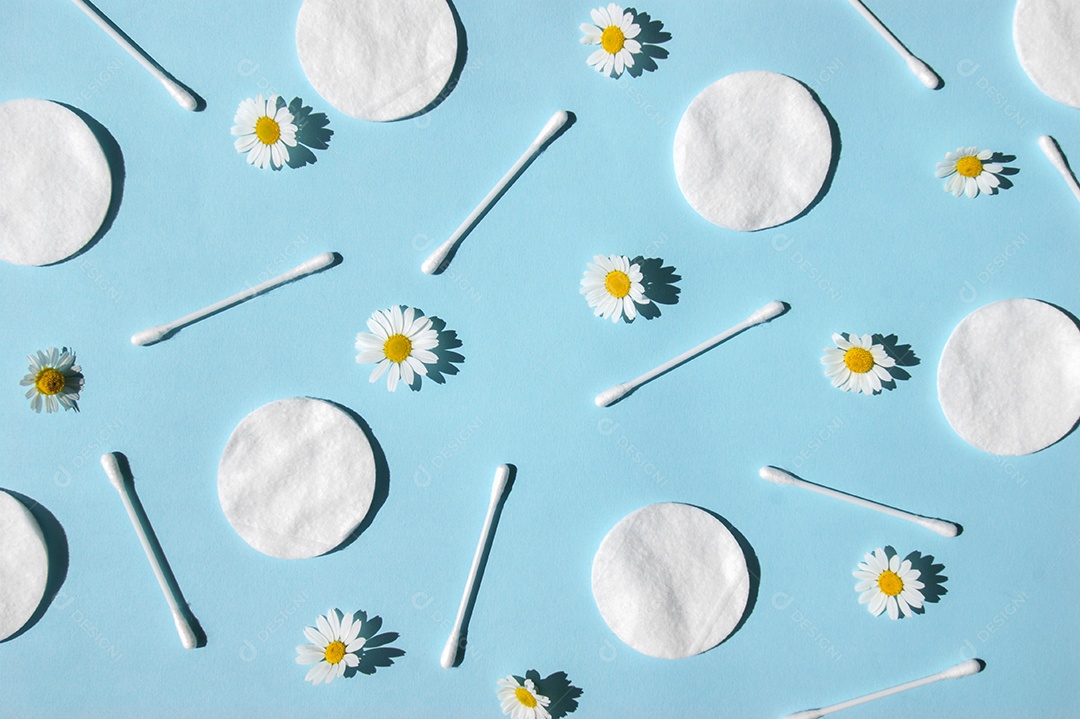 Disco de algodão e cotonetes espalhados sobre fundo azul