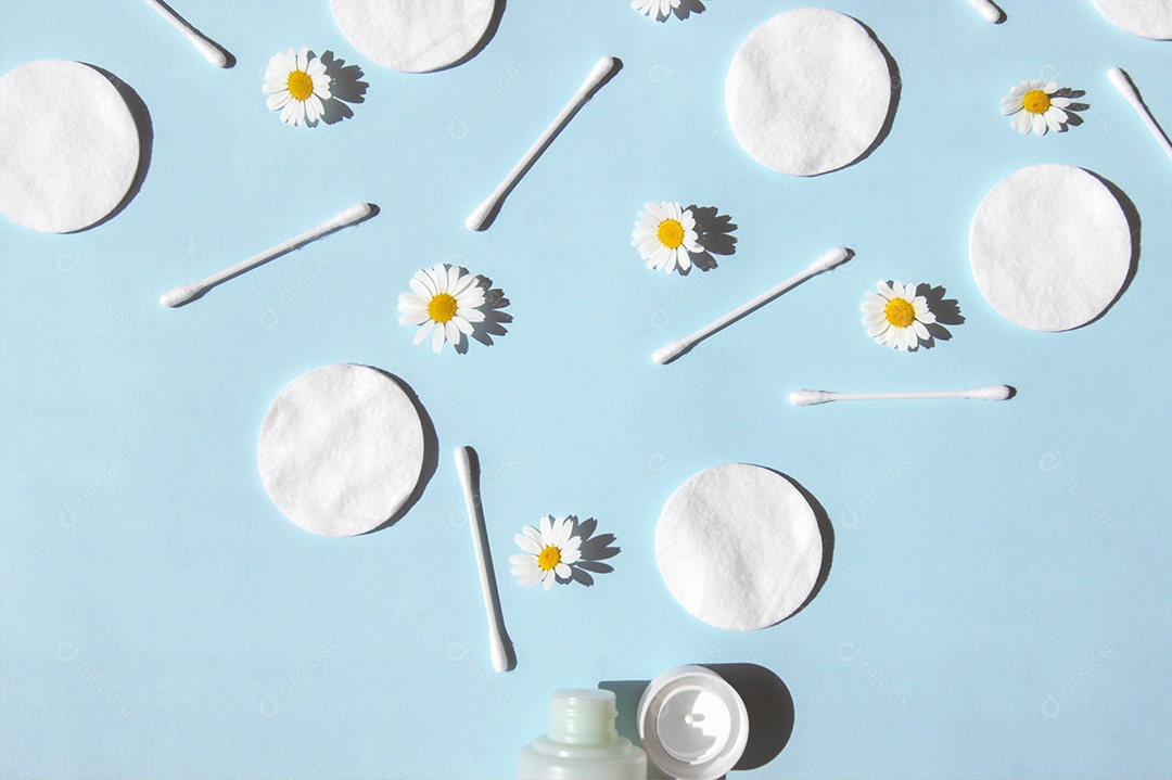 Disco de algodão e cotonetes espalhados sobre fundo azul