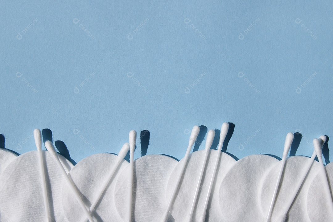 Disco de algodão e cotonetes sobre fundo azul