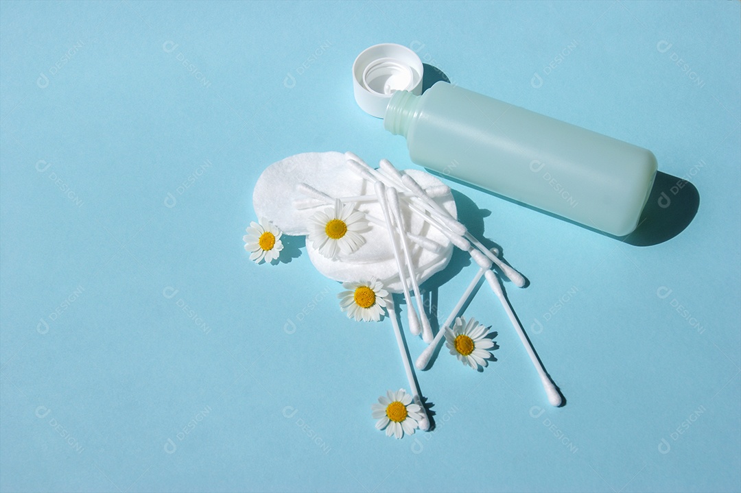 Almofadas de algodão e cotonetes com vidro de demaquilante caído