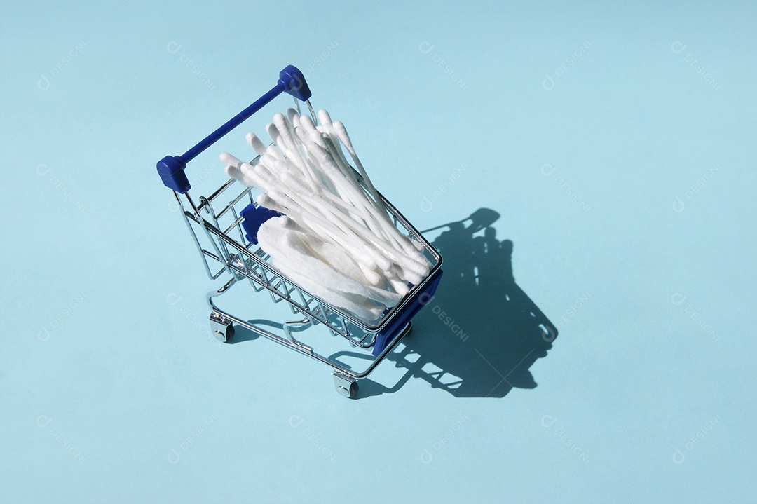 Carrinho de compra com cotonetes sobre fundo azul claro