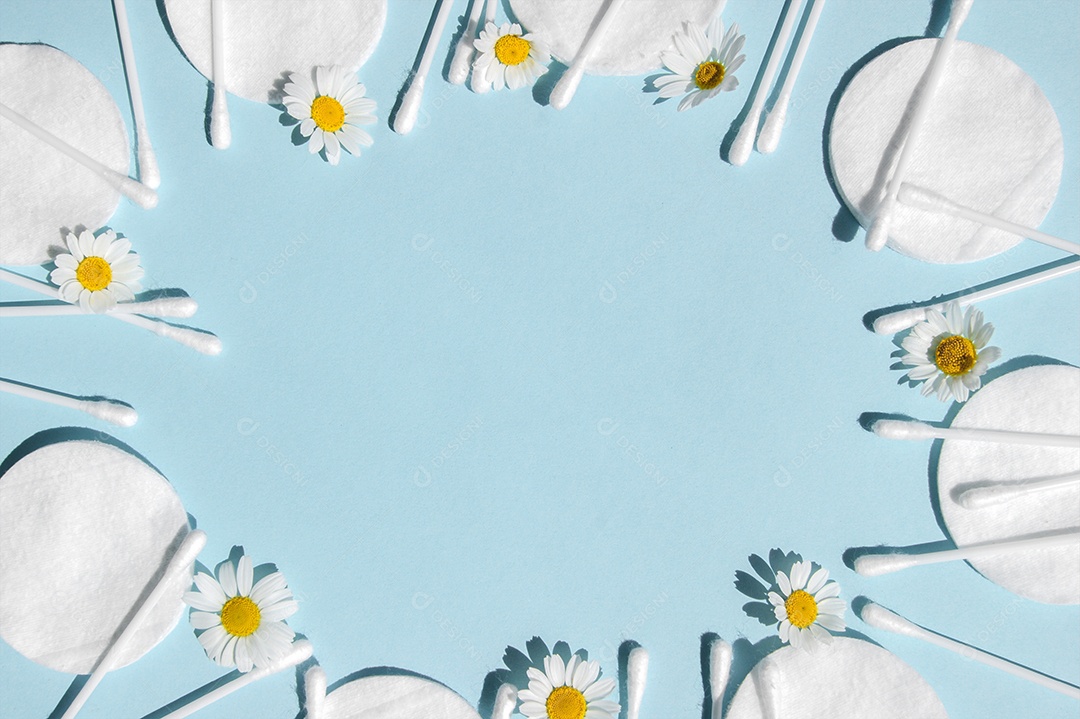 Cotonetes e disco de algodão e flor de camomila sobre fundo azul claro