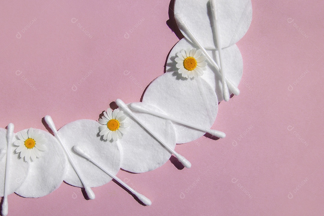 Disco de algodão e cotonetes sobre fundo rosa