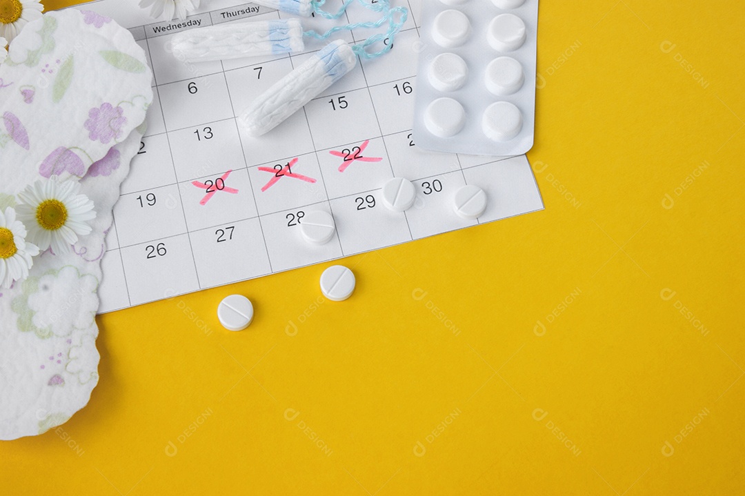Absorventes calendário e comprimidos sobre fundo amarelo