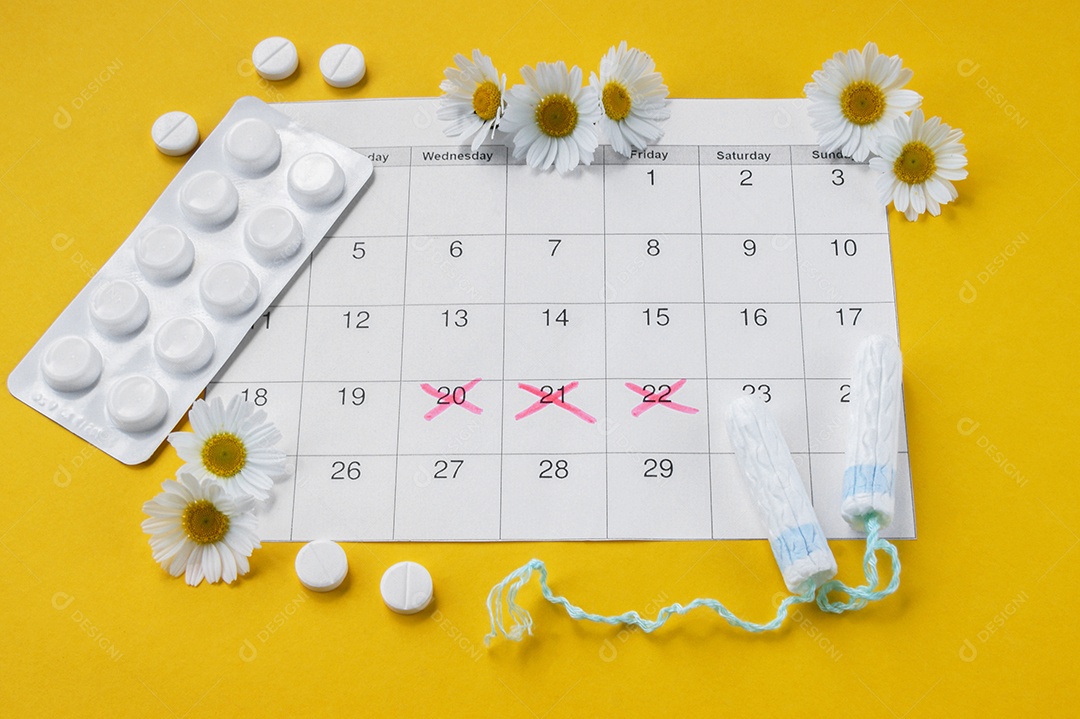 Cartelas de remédio em cima de calendário marcado e absorventes