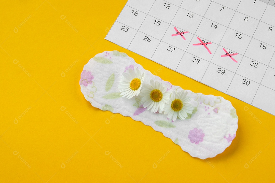 Calendário marcado e absorvente diário camomila sobre fundo amarelo