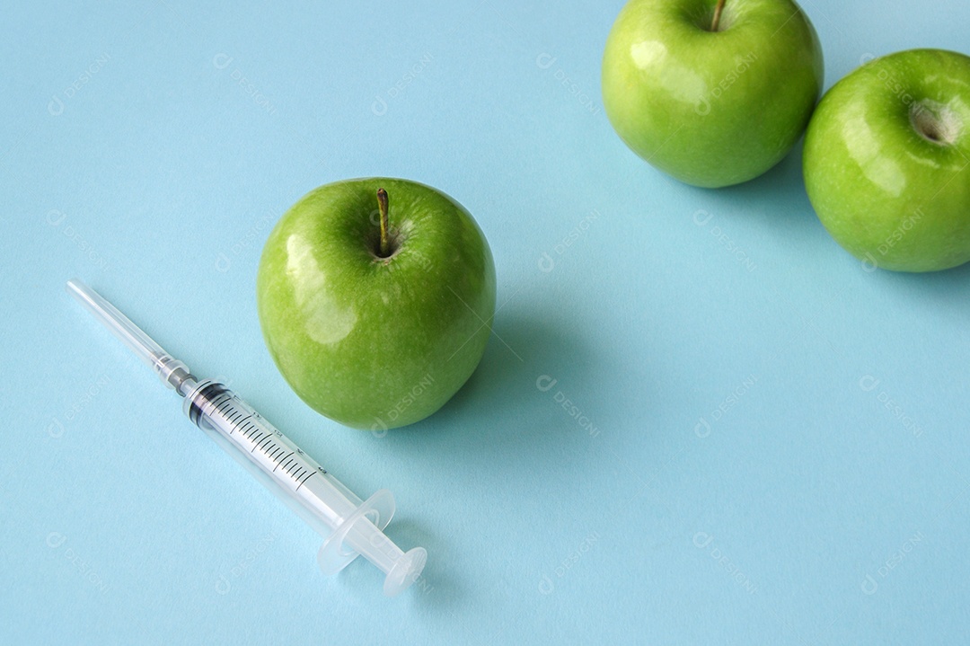 Maçãs verde e seringa sobre fundo azul
