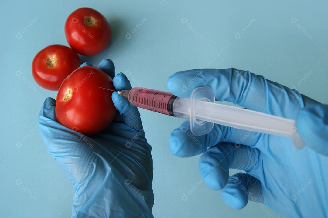 Mãos segurando e injetando algo em tomates