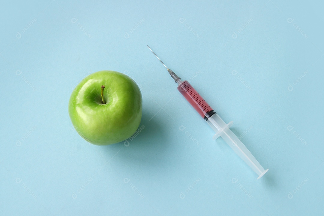 Maçã verde e seringa sobre fundo azul